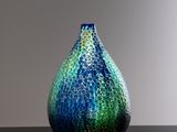 a blue and green vase sitting on a black table