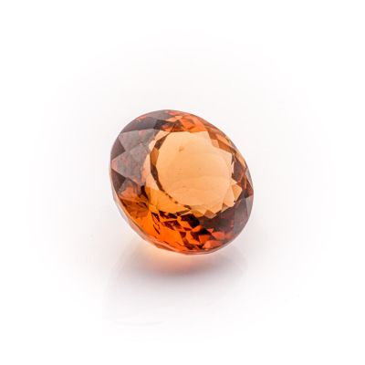 a close up of an orange sapphire stone on a white surface