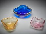 trois bols en verre de couleurs différentes posés sur une surface blanche