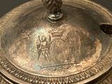 a silver vase with a lid that has a picture of a man on it