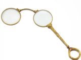 une paire de lunettes loupes plaquées or sur fond blanc