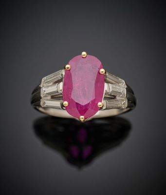 une bague ovale sertie d'un rubis et de diamants en taille baguette sur un fond noir