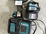 une perceuse filaire et deux batteries posées par terre