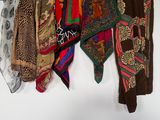 many different types of scarves hanging on a wall