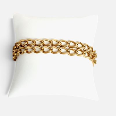 gros plan d'un bracelet en chaîne en or sur un oreiller
