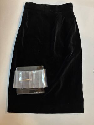 La jupe est noire et comporte une boucle argentée sur le devant.
