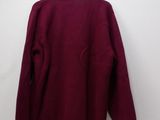 a red sweater hanging on a hanger against a white wall