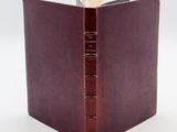 un livre ouvert, avec une couverture marron, posé sur une table blanche