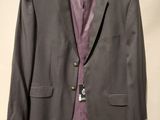 grey suit with purple shirt hanging on a hanger in a room