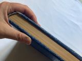 a person holding a book in their hand on a bed