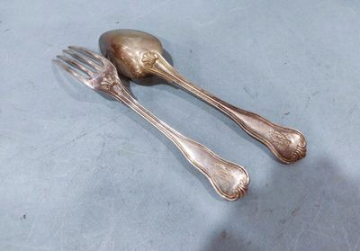 two silver spoons and a fork on a table