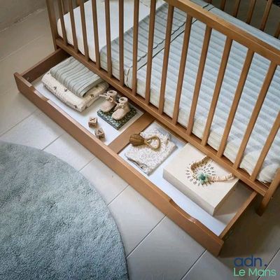 un lit de bébé avec un sommier et un tiroir en dessous