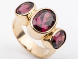 a close up of a gold ring with three oval garnets
