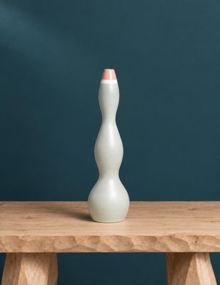 un vase blanc posé sur une table en bois, près d'un mur bleu
