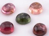six pierres précieuses de couleurs différentes sont disposées en ligne sur une surface blanche