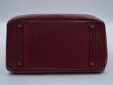 a red leather bag sitting on top of a white surface