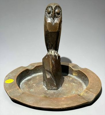 an image of a bronze owl statue sitting on top of a metal plate