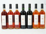 six bouteilles de vin sont alignées sur une surface blanche