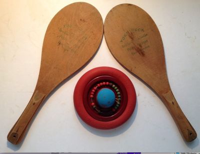 Deux cuillères en bois sont posées sur une table, à côté d'un bol rouge.