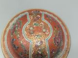a small orange plate with a decorative design on it