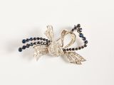 une photo d'un collier de perles bleues et blanches orné d'un nœud en argent