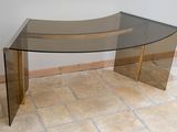 a glass table with a curved glass top on a tile floor