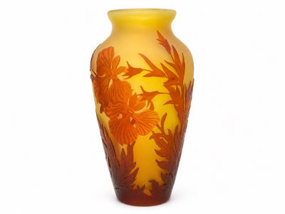 un vase jaune orné de fleurs orange sur fond blanc