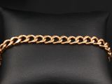 un bracelet en chaîne d'or posé sur un coussin en cuir noir