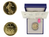 an image of a gold coin in a blue box with a pink ribbon