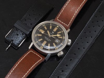 a black watch with a brown strap on a black surface