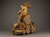 a gold clock with a statue on top of it