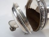 a silver container with a lid on a white surface