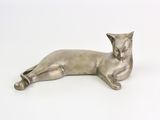 une statue en argent représentant un chat couché sur une surface blanche