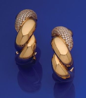 une paire de boucles d'oreilles en or jaune et diamants sur un fond bleu