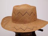 un chapeau de paille troué posé sur un support en bois