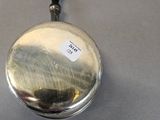 a small silver plate with a black handle on a table