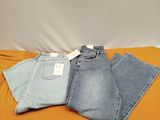 trois paires de jeans posées sur un lit recouvert de draps orange