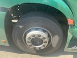 a green bus with a flat tire parked on the street