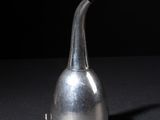 a silver pitcher sitting on a table with a black background