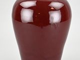 a large red vase sitting on a white surface