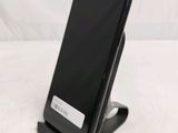 a black cell phone sitting on a stand on a table