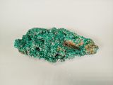 a close up of a piece of green mineral on a white surface