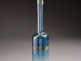 blue glass bottle with a gold rim on a white surface