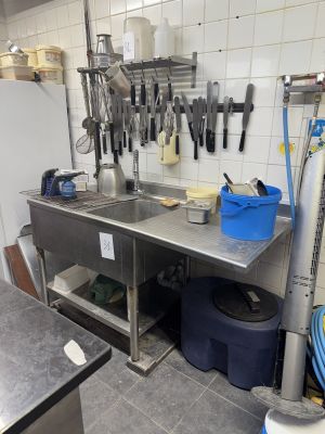 une cuisine avec un évier et un plan de travail sur lequel sont posés tout un tas d'ustensiles
