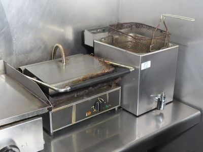 stainless steel counter top with two deep fryers on top of it