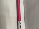 un stylo rose posé sur un mur blanc