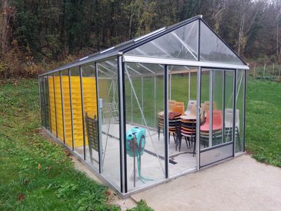une serre en verre avec une table et des chaises à l'intérieur