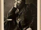 photographie en noir et blanc d'un homme barbu assis sur une chaise