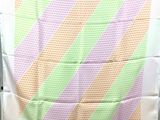 une chaise blanche recouverte d'une couverture rayée verte et rose