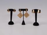 three pairs of gold earrings on black stands